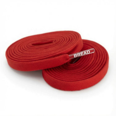 Two coiled red fabric shoelaces with clear plastic tips featuring the white printed text BREAD.