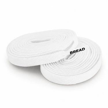 Two white woven elastic shoelaces coiled on a white background, with the brand name 'BREAD' printed in black on one lace.
