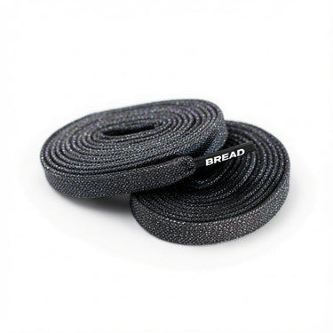 Two coiled flat black sparkly fabric shoelaces with BREAD printed on the plastic aglet.