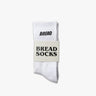 White crew socks with "BREAD" printed in black on the cuff, packaged with a label reading "BREAD SOCKS.