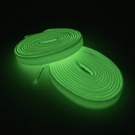 Glow-in-the-dark elastic shoelaces in a coiled design, emitting a bright green light against a dark background.